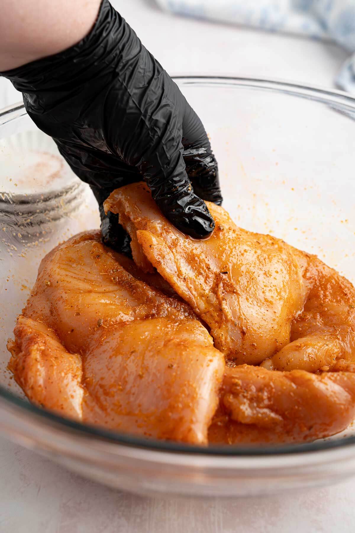 mixing seasoned chicken breasts in a bowl