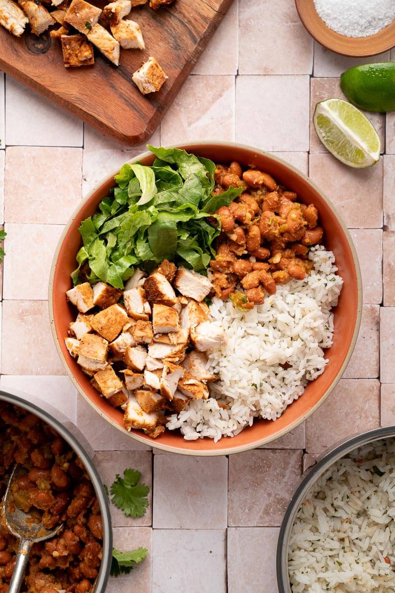 bowls with chicken, pinto beans, lettuce, and rice 