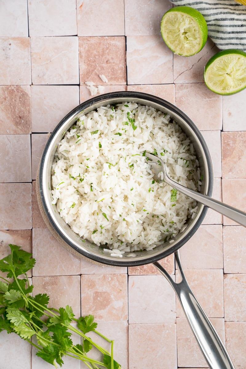 fluffy rice in pot with cilantro and lime