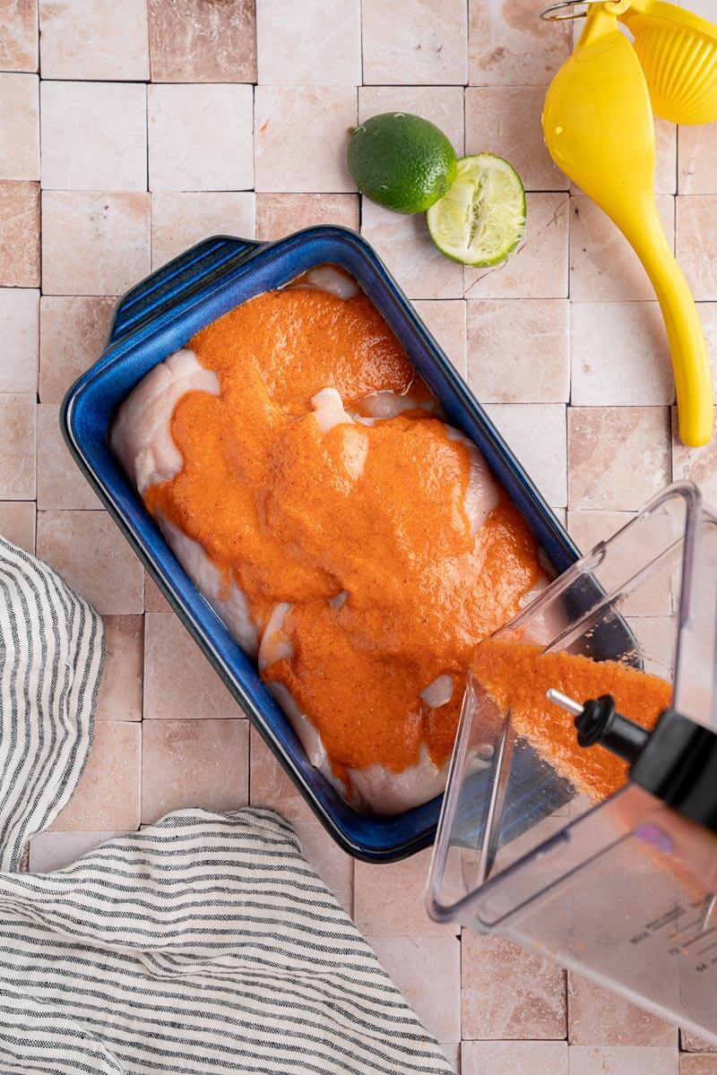 chipotle chicken marinade being poured over chicken to marinate