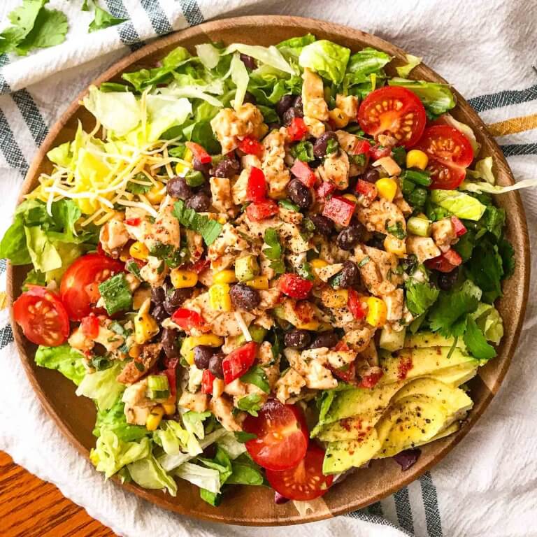 southwest chicken salad on a bed of lettuce with avocado and tomatoes