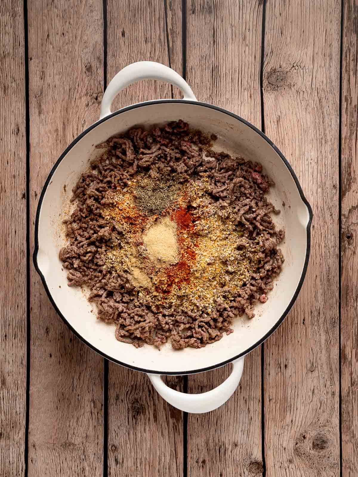 Ground beef with seasonings in a pan.