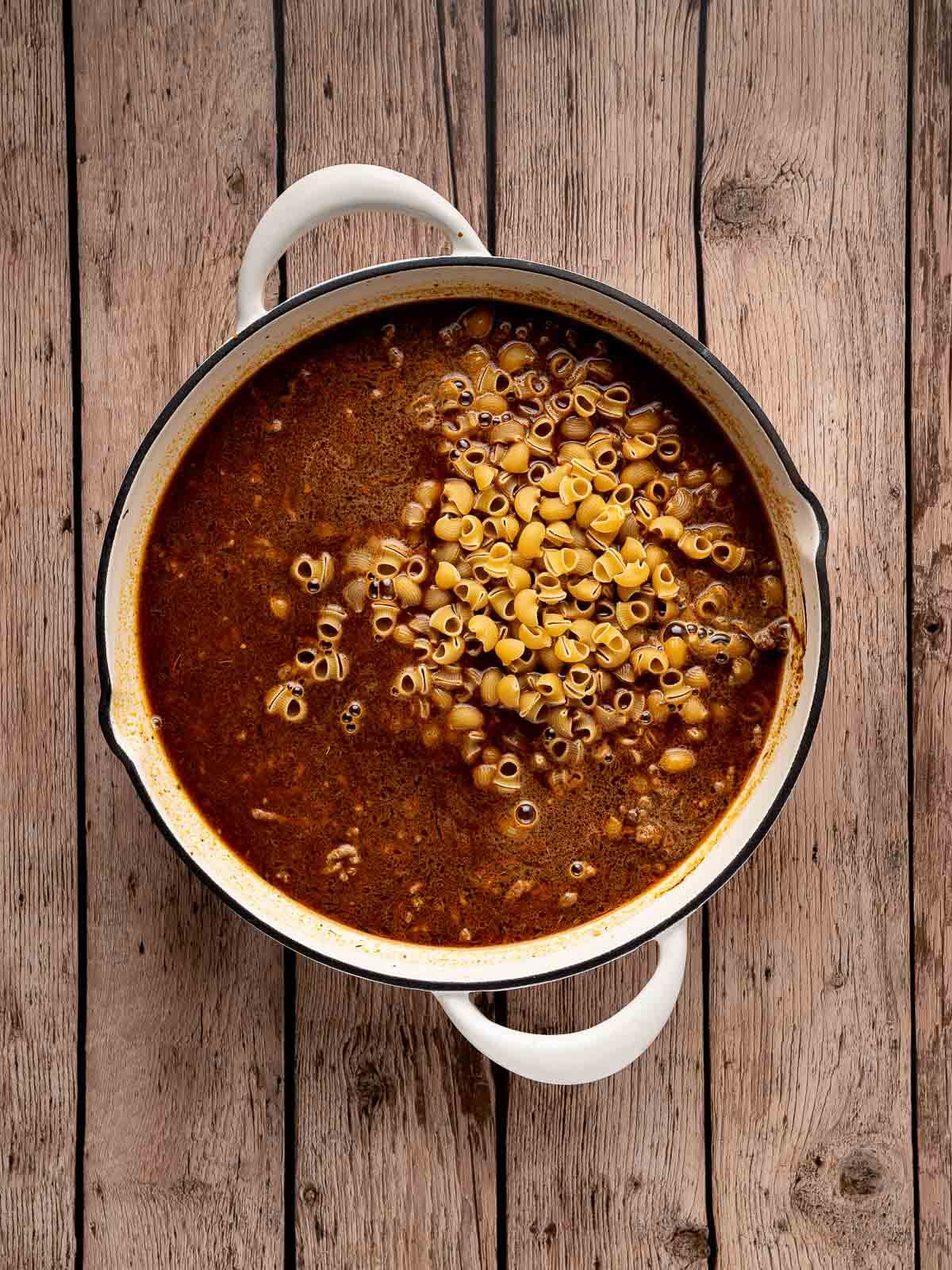 noodles covered in beef broth in a large skillet.