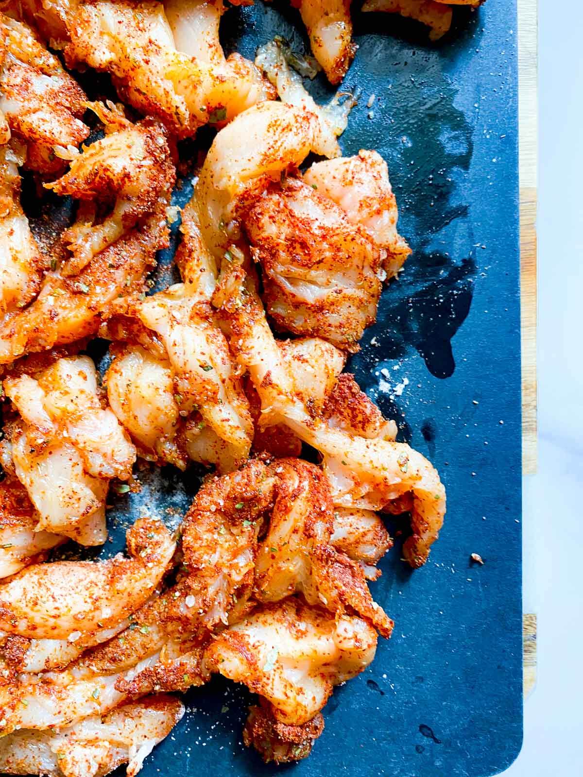 thinly sliced raw chicken on cutting board with seasonings.