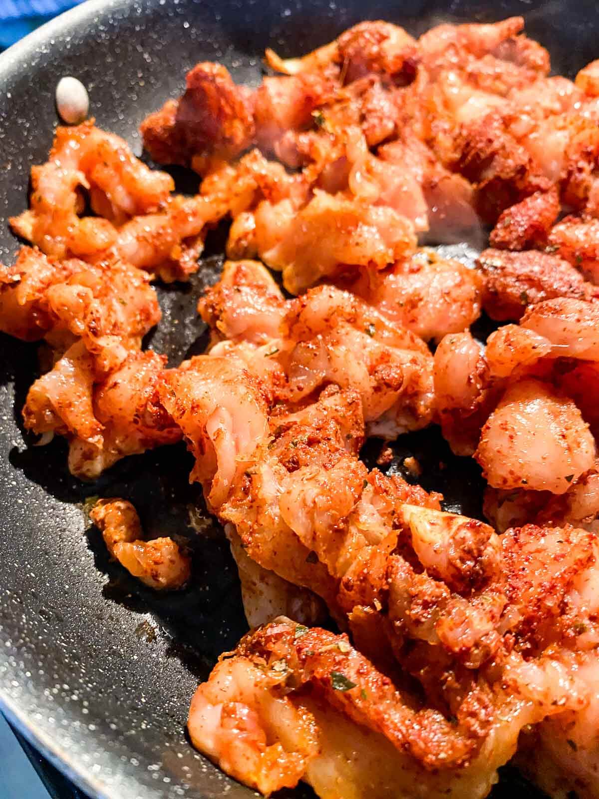 thinly sliced and seasoned raw chicken in a skillet cooking.