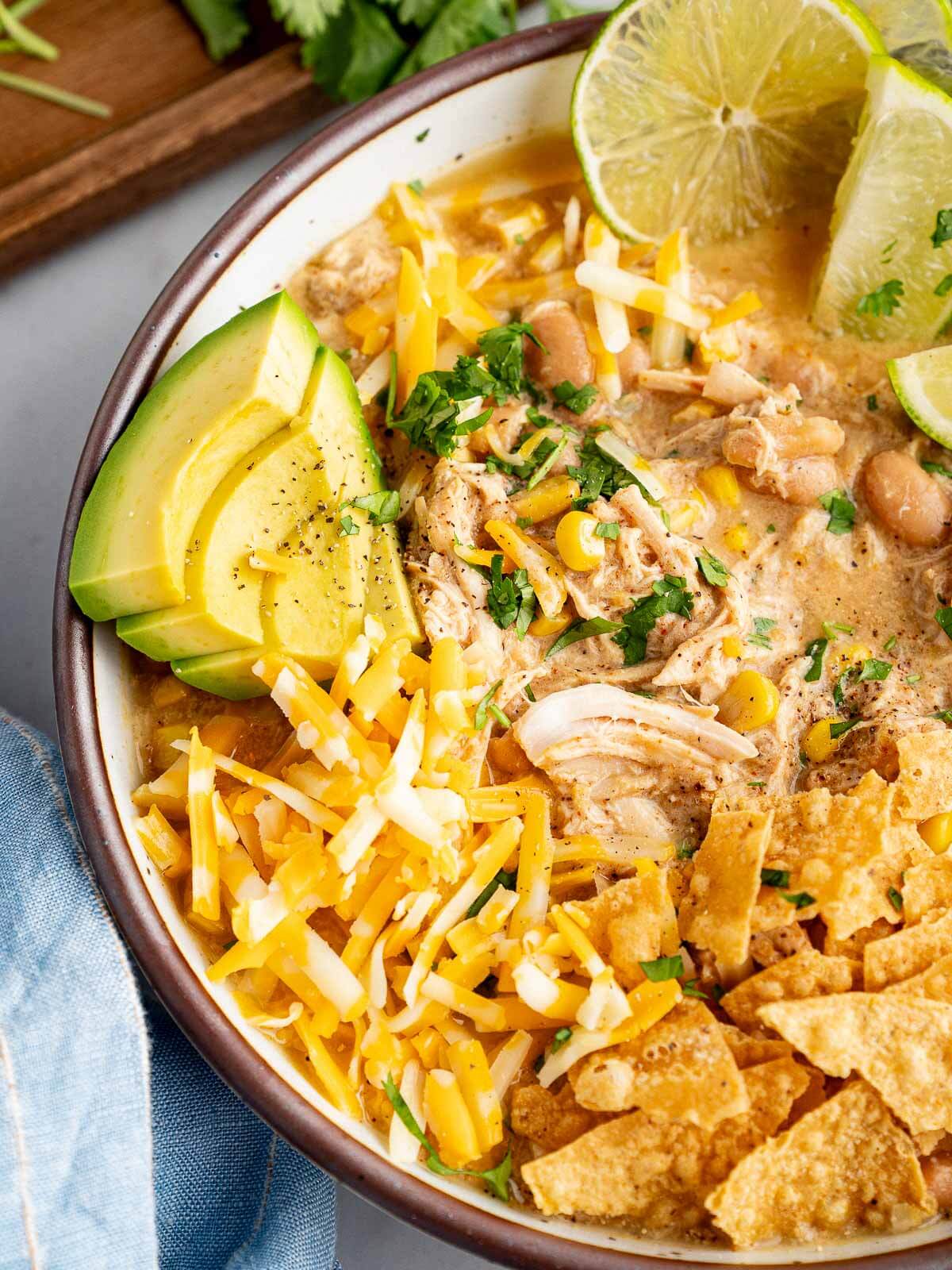 creamy white chicken chili with avocado, shredded cheese, and tortilla chips.