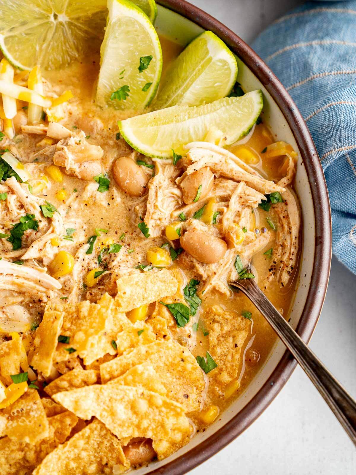 Creamy Crockpot white chicken chili topped with tortilla chips, cilantro, and fresh lime.