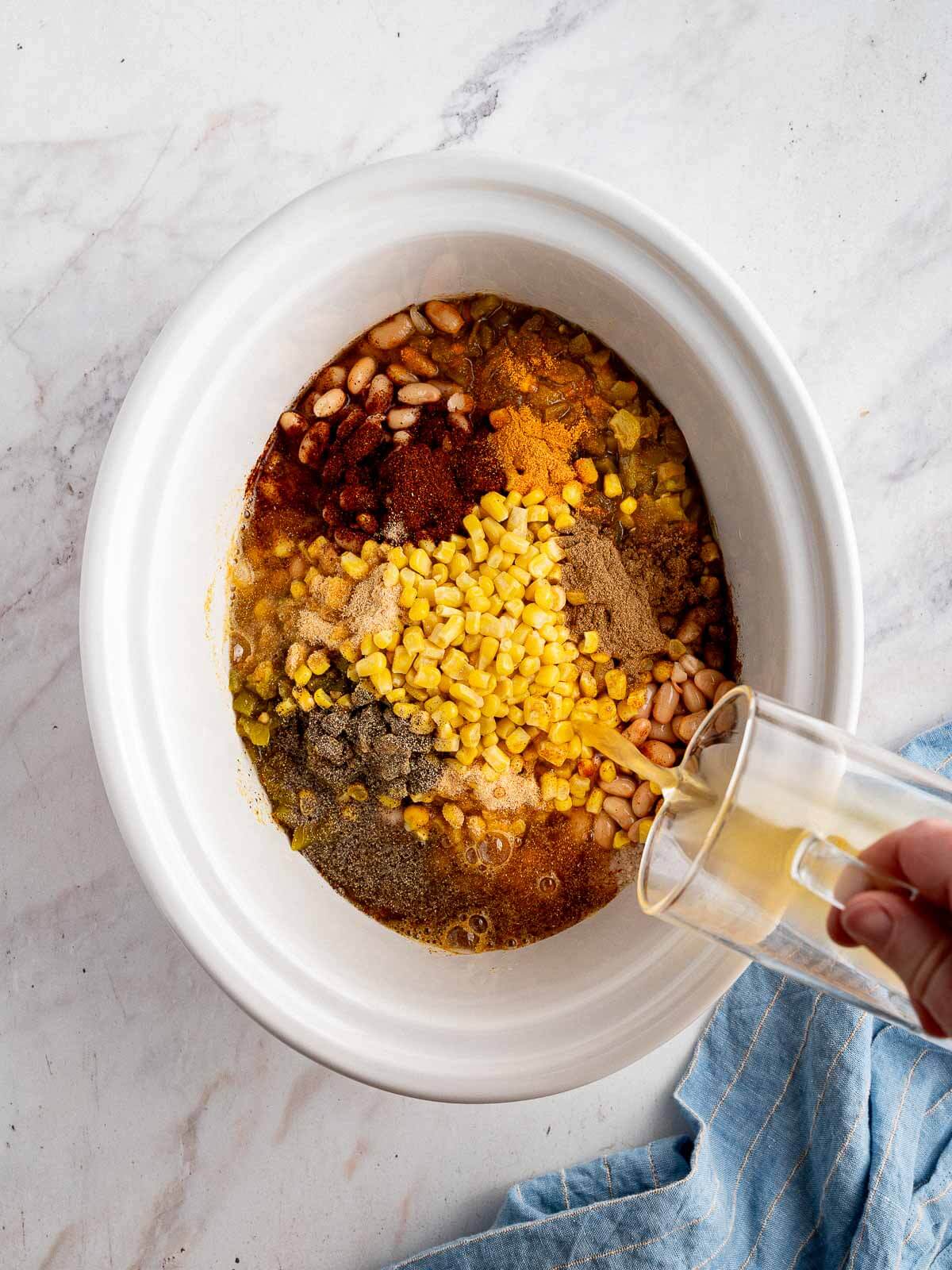 crockpot with corn, bean, chicken, and spices. 