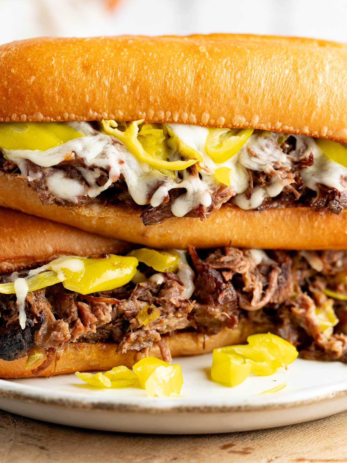 italian beef sandwiches stacked together with melty cheese and fresh Pepperoncini.