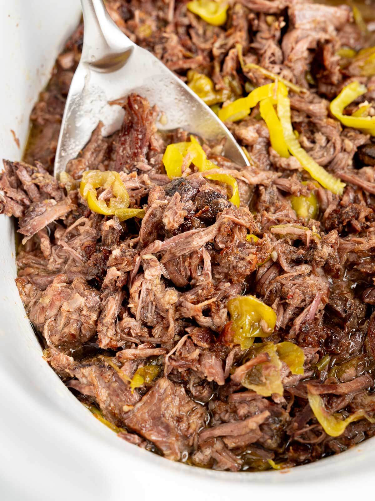 italian beef in slow cooker with a spoon. 