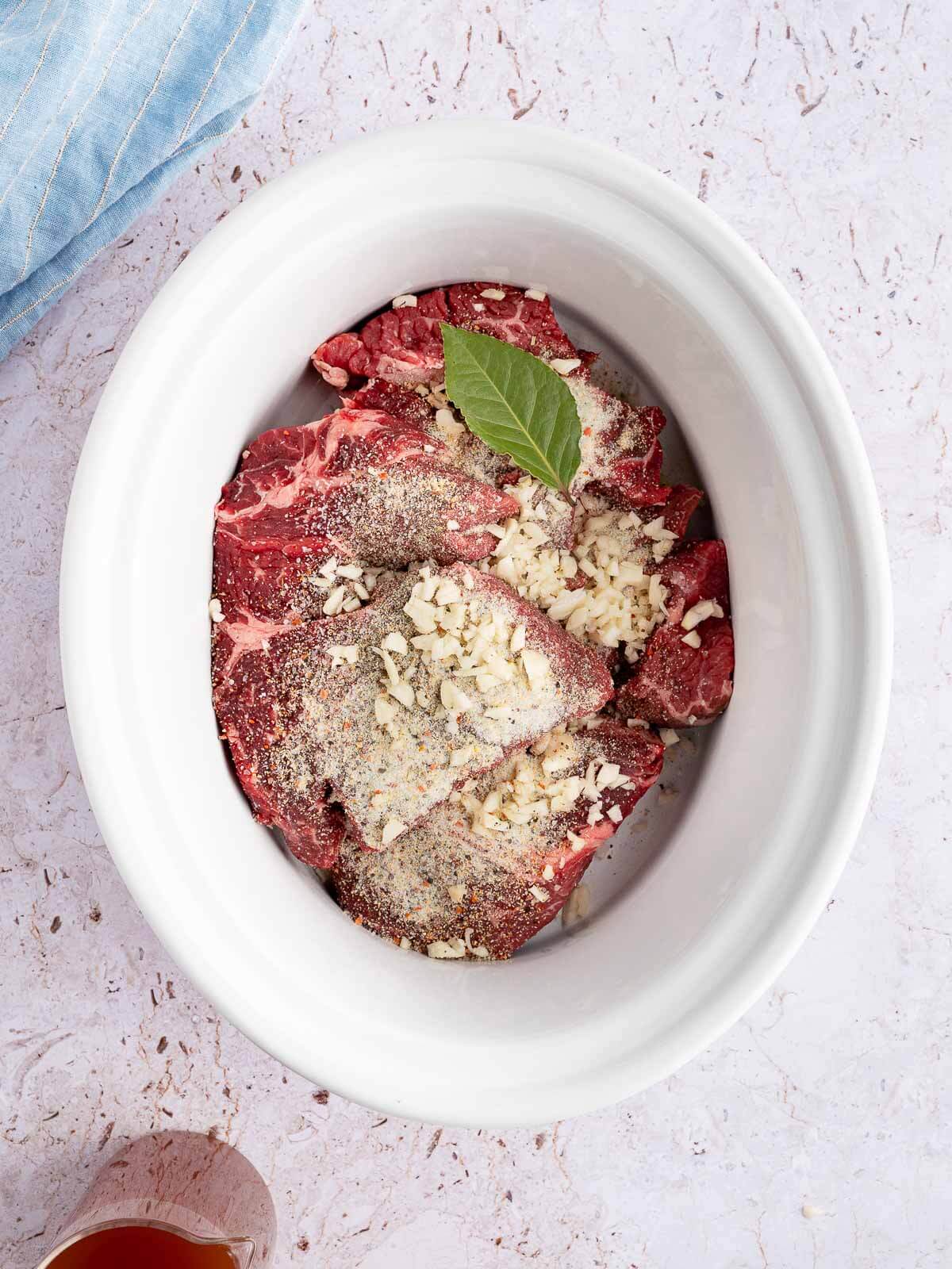chuck roast in crockpot with italian seasoning mix, minced garlic, and bay leaf.