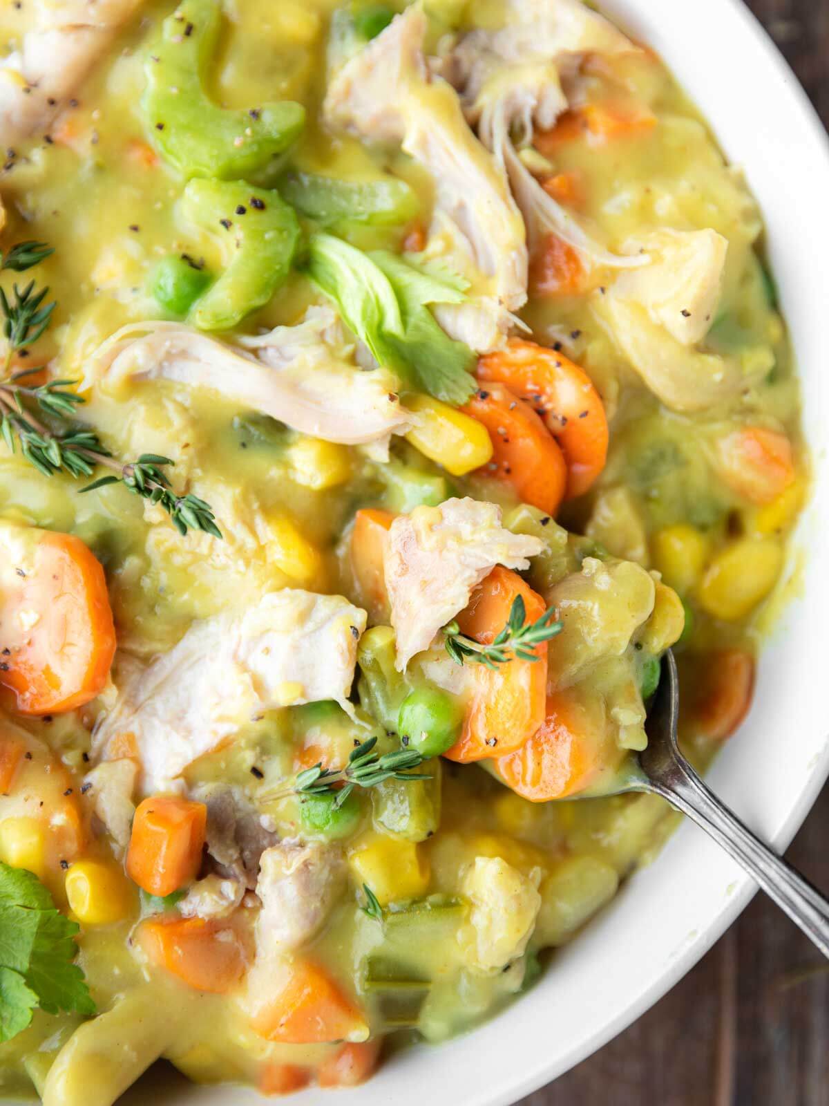Spoon dipping into a bowl of creamy chicken pot pie soup.