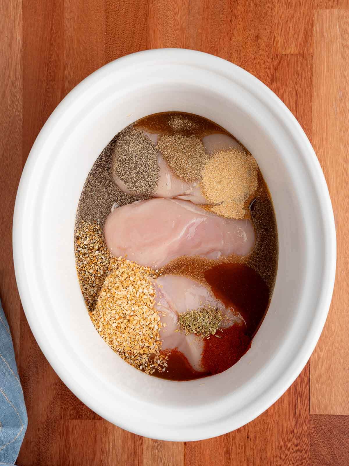 chicken breasts in crockpot with seasonings.