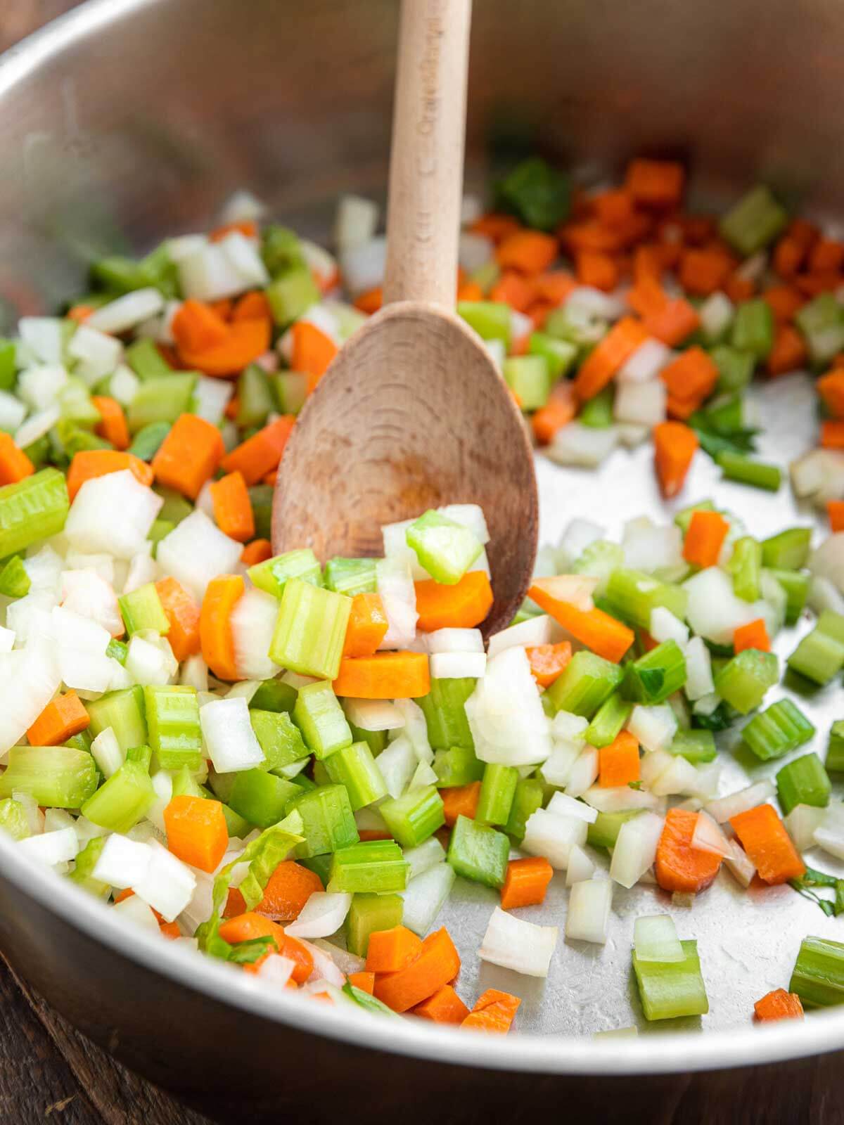 Diced carrots, celery, and onion sautéing in a large pot.