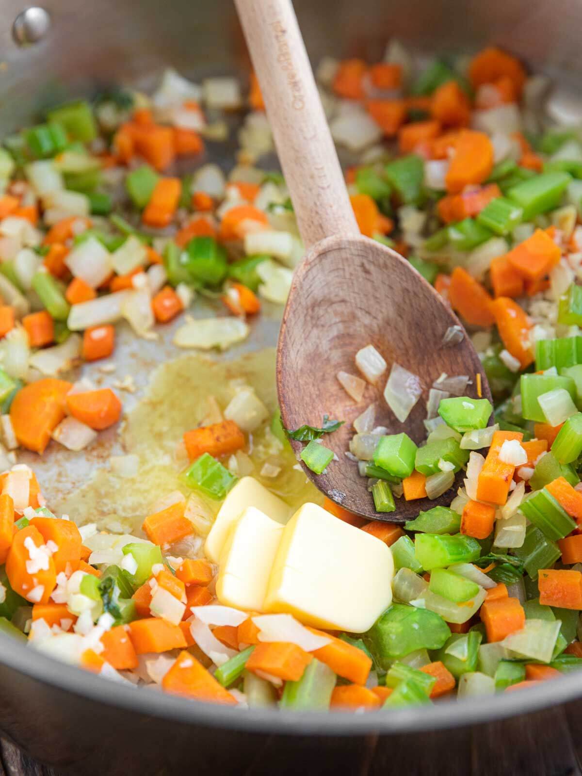 Butter melting into sautéed carrots, celery, and onion.